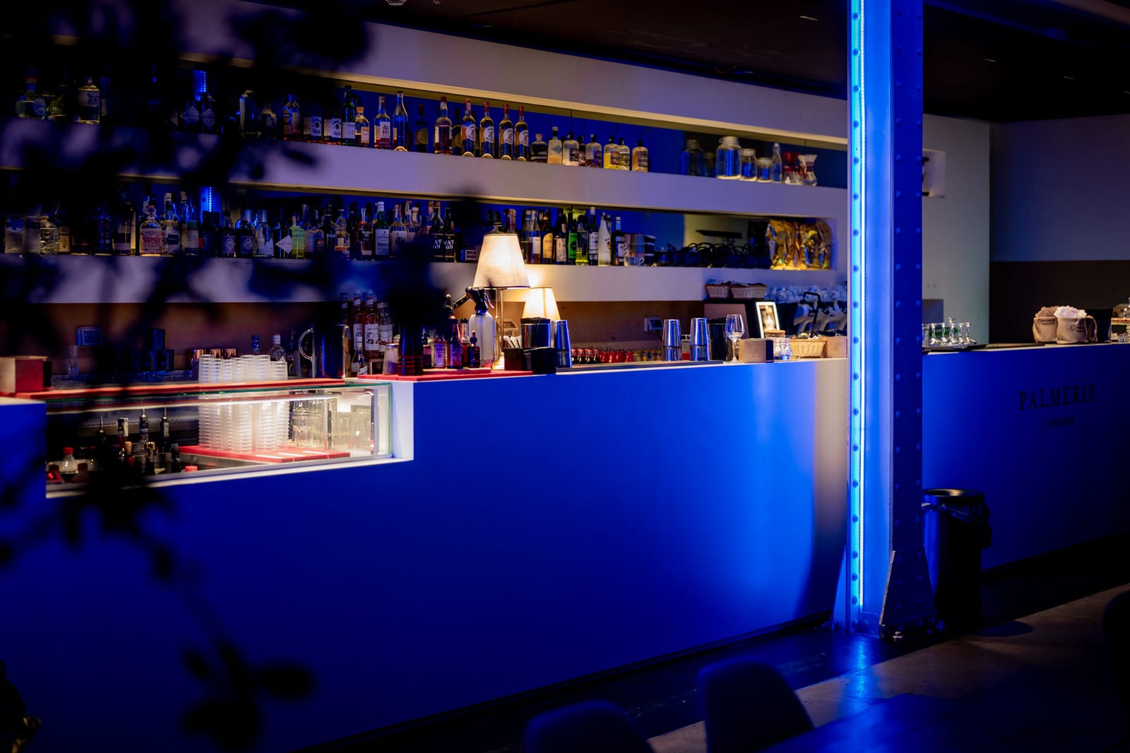 Bancone del cocktail bar di un locale per eventi con bottiglie retroilluminate e luci blu - fotografia di locali commerciali