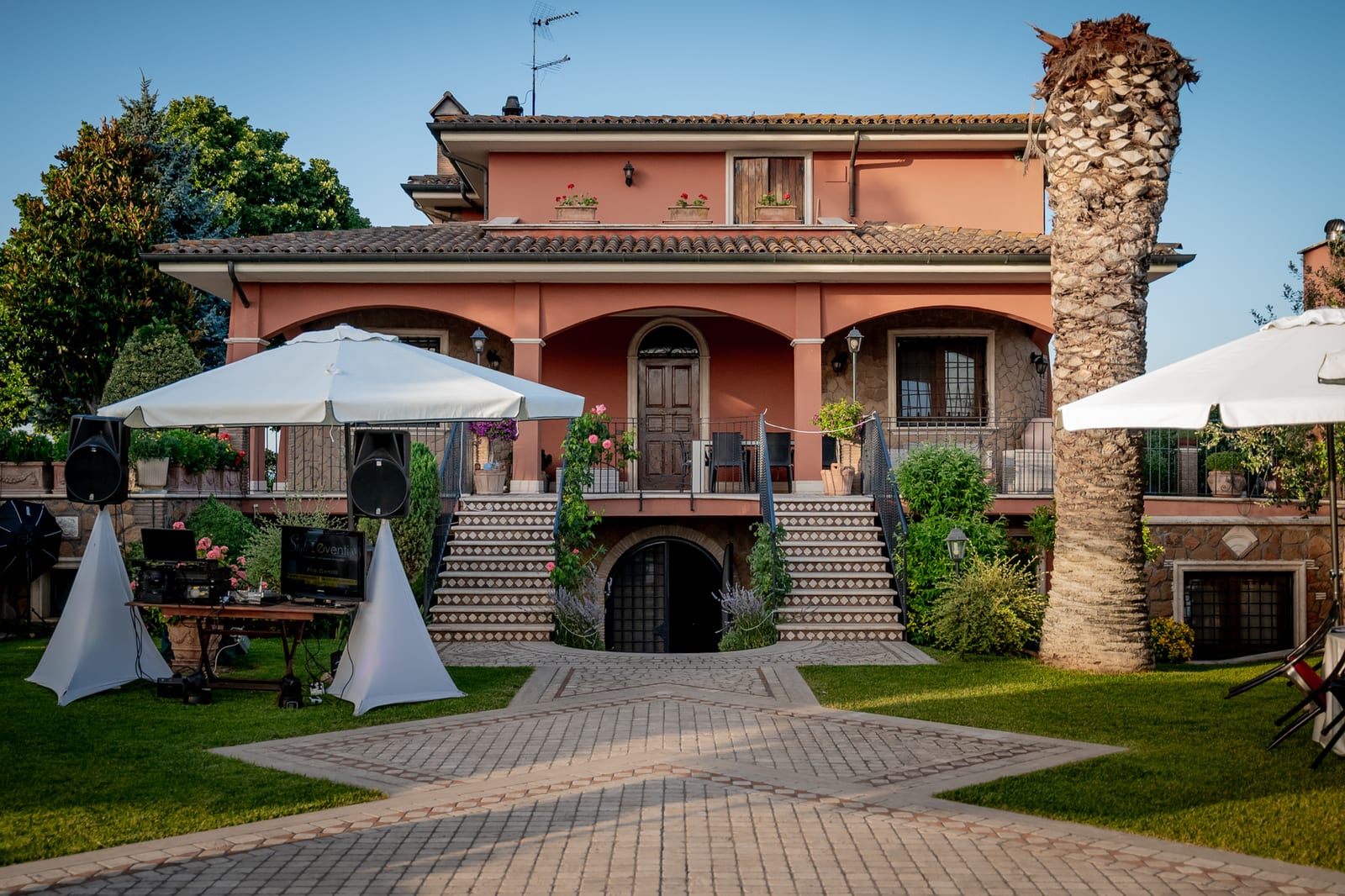 Facciata di una villa a due piani con porticato, scalinate e giardino con vialetto in pietra - fotografia immobiliare di esterni